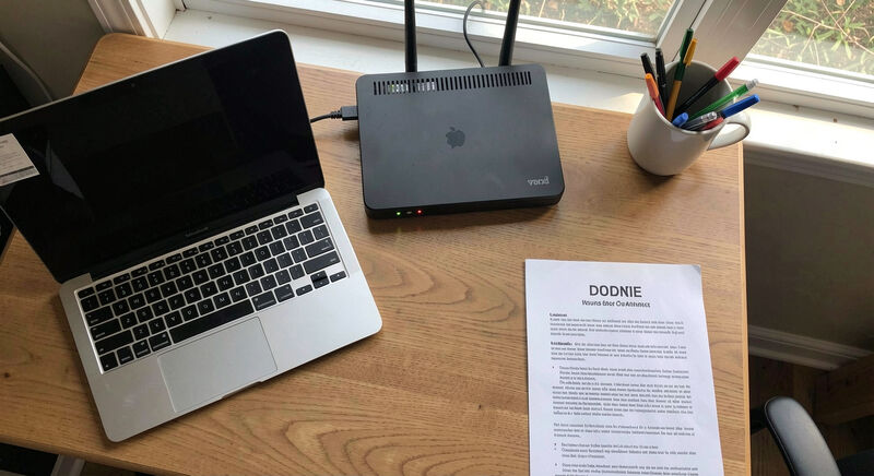 A volunteer's desk in a church office on a weekday morning, an open MacBook showing a SQL table of event listings, a paper notebook beside it, soft window light from the left.